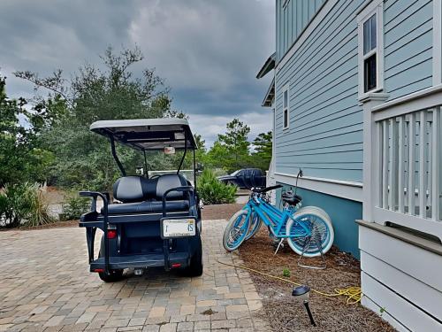 a golf cart parked next to a house with a bike at Emerald Escape in Blue Gulf Beach