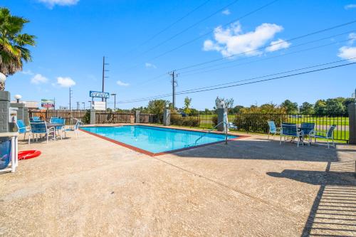 a swimming pool with blue chairs and a fence at Americas Best Value Inn & Suites-Livingston in Livingston