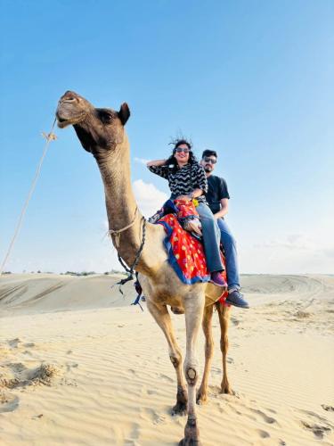two people riding on a camel in the desert at Hotel Robin Jaisalmer Near fort view in Jaisalmer
