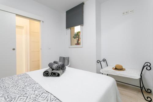 Un dormitorio blanco con una cama y una silla. en La Casita De Yessy, en Alicante
