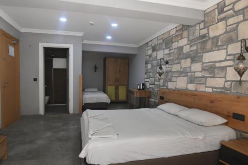 a bedroom with two beds and a stone wall at Ballı Butik hotel in Kayakoy