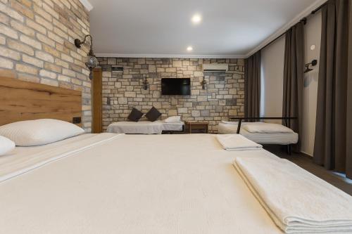 a bedroom with two beds and a brick wall at Ballı Butik hotel in Kayakoy
