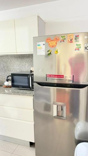 a stainless steel refrigerator in a kitchen next to a microwave at The Legends Family Apartment in Lima