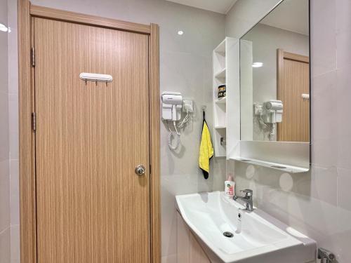 La salle de bains est pourvue d'un lavabo et d'une porte en bois. dans l'établissement Forest City Near Marina Hotel - Kylin Apartment, à Gelang Patah