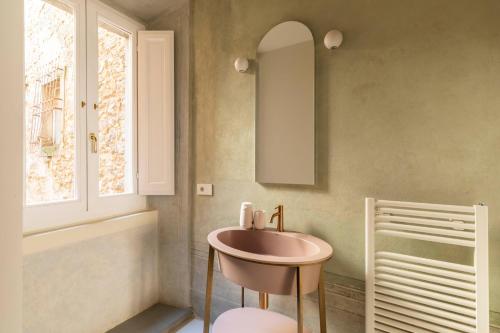 ein Bad mit einem rosa Waschbecken und einem Fenster in der Unterkunft Ruga23 -1 in Cortona
