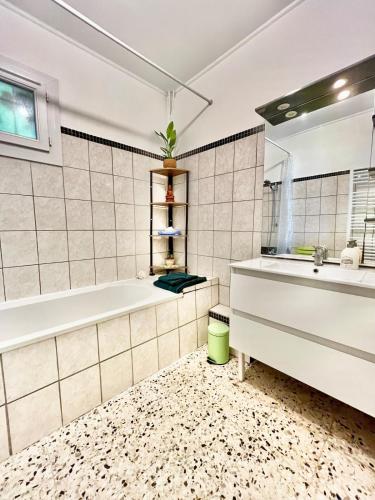 a bathroom with a tub and a sink at T2 cosy avec jardin privé et terrasses au calme in Cabriès