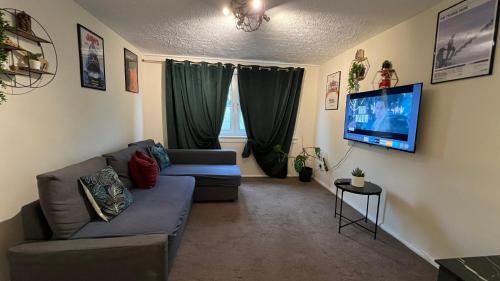 a living room with a couch and a flat screen tv at The Red Door, Two-Bedrooms Apartment in Edinburgh