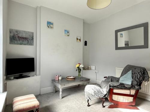 a white living room with a chair and a tv at 2 Bedroom House Penarth Town Centre in Cardiff