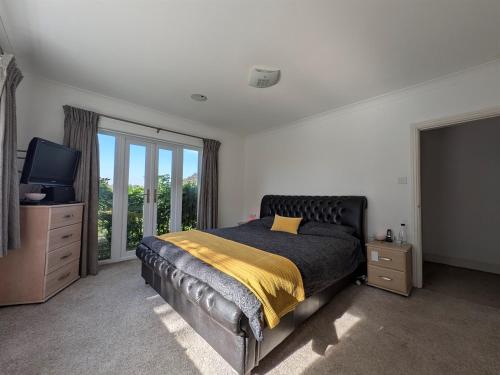 a bedroom with a bed and a tv and windows at Aberfall Private Luxury Villa Indoor Pool Hot Tub Gym Cinema in Goxhill