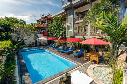 una piscina in un hotel con sedie e ombrelloni di Waroeng Surya Home Stay a Uluwatu