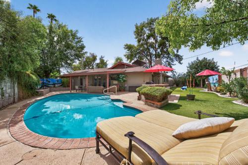 a swimming pool with a couch and a house at Pineapple Oasis - Heated Pool, ASU, Sleeps 12 in Tempe