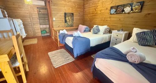 a bedroom with two beds in a log cabin at Posada Las Maravillas in Punta Del Diablo