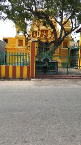 a yellow and red fence with a tree and a building at The villa sunshine kadawala in Dunagaha