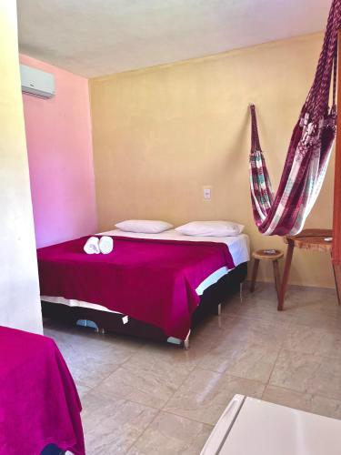 a bedroom with a bed with purple sheets and pillows at Recanto flor do maracujá in Ubajara