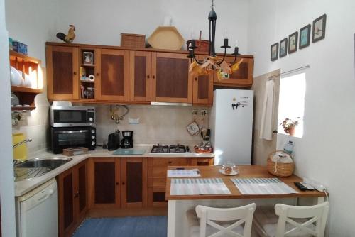 a kitchen with wooden cabinets and a table and a refrigerator at Casinha Amarela in Sintra