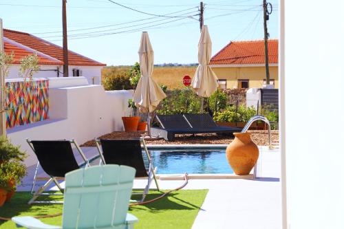 a patio with chairs and umbrellas next to a pool at Casa do Campinho B&B boutique country house in Reguengos de Monsaraz