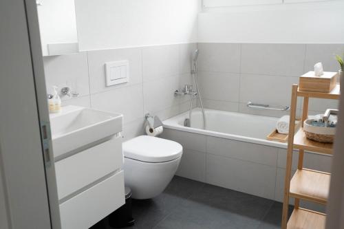 a white bathroom with a toilet and a bath tub at SimpleSparks I Luzern I Andermatt I Natur I Family in Altdorf