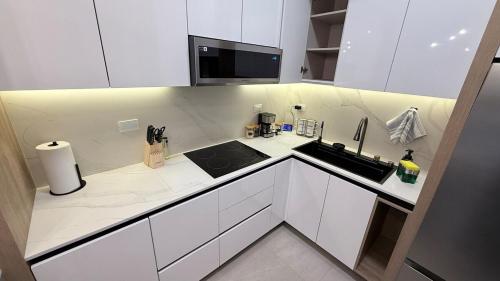 a white kitchen with a sink and a microwave at Luxury apartment 2 minutes from BBVA Stadium in Monterrey