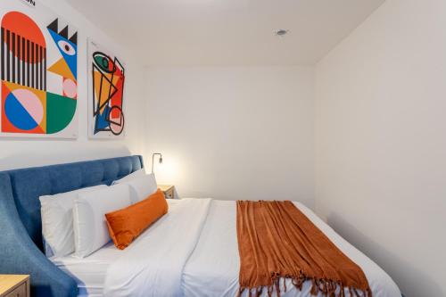 a bedroom with a white bed with an orange pillow at Artful 3BR in Montreal Village in Montréal