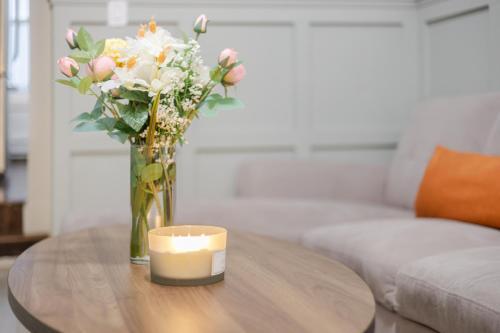 a vase of flowers and a candle on a table at Artful 3BR in Montreal Village in Montréal