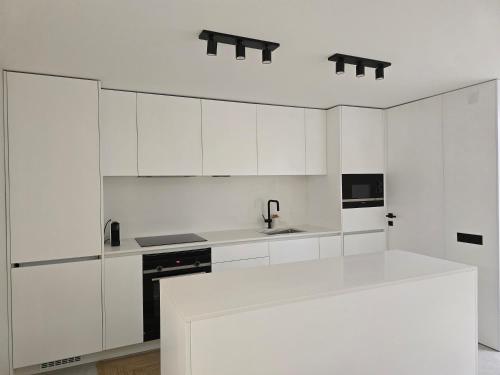 a white kitchen with white cabinets and a sink at SecretWaters Studio in São Jacinto