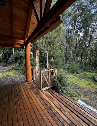 a wooden deck with a wooden bench on it at Cabañas Alto del Bosque in Coñaripe