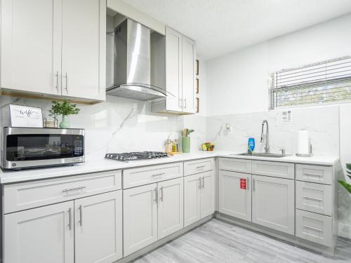 a white kitchen with white cabinets and a microwave at Dora's Haven Getaway-Cozy 1Bedroom with Boat or Camper Parking- Free in Mount Dora