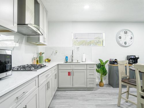 a kitchen with white cabinets and a clock on the wall at Dora's Haven Getaway-Cozy 1Bedroom with Boat or Camper Parking- Free in Mount Dora