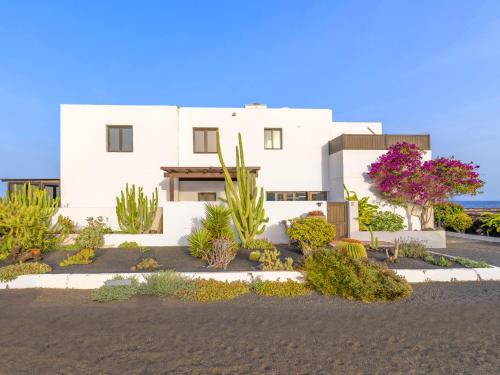 Una casa blanca con plantas delante de ella. en Volcán de sal, en Teguise