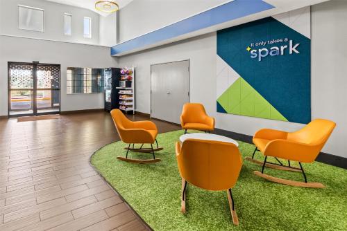a waiting room with orange chairs and a table at Spark by Hilton Round Rock in Round Rock