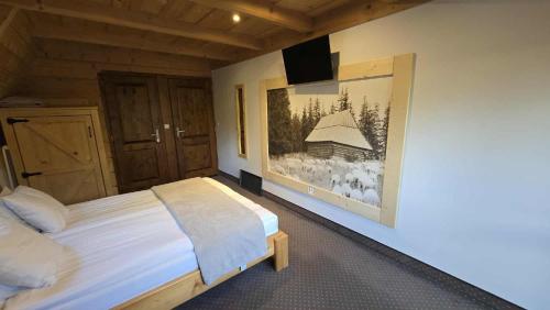 a bedroom with a bed and a painting on the wall at Chocholowska Zohylina pokoje in Chochołów