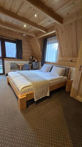 a bedroom with a large bed in a room with wooden ceilings at Chocholowska Zohylina pokoje in Chochołów