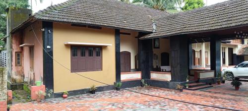a small yellow house with a brown door on a street at Vintage Vista in Lakkidi