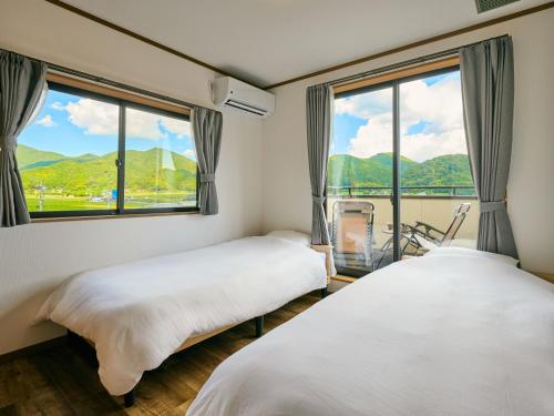 two beds in a room with a large window at 美祢Terrace in Mine