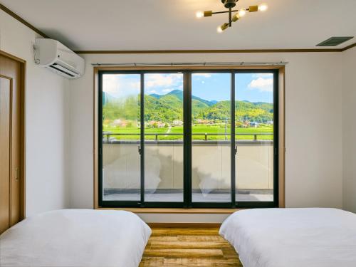 two beds in a room with a large window at 美祢Terrace in Mine