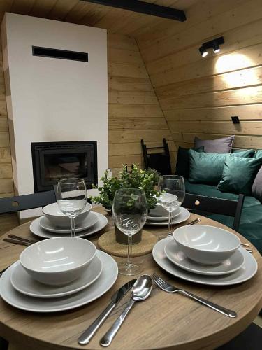 a wooden table with plates and wine glasses on it at Brda 5 osobowa z jacuzzi in Zawoja