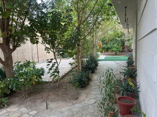 a courtyard with trees and plants and a fence at AL- aqyr Rest Garden أستراحة حارة العقر in Nizwa