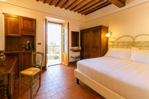 a bedroom with a bed and a desk and a window at L'orto Delle Terme in Bagno Vignoni