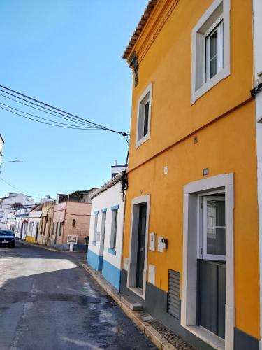 a street in an old town with colorful buildings at Yellow House in Tavira