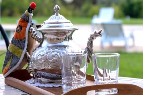 a tea pot and two glasses on a table at Dar hamama - Villa familiale - Marrakech in El Aggada