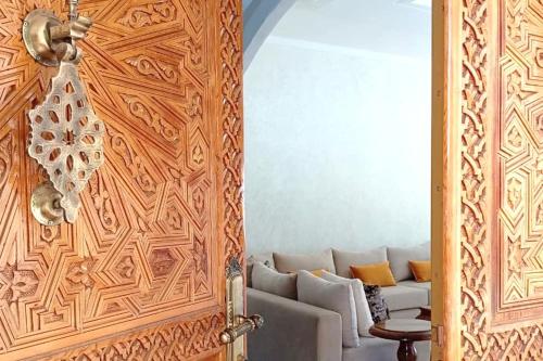 a living room with a couch behind a wooden door at Dar hamama - Villa familiale - Marrakech in El Aggada