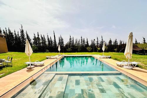 a swimming pool with chairs and umbrellas in a yard at Dar hamama - Villa familiale - Marrakech in El Aggada