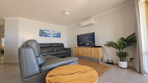 ein Wohnzimmer mit einer Ledercouch und einem Tisch in der Unterkunft Pelican Shore Villa 3A- Kalbarri, WA in Kalbarri