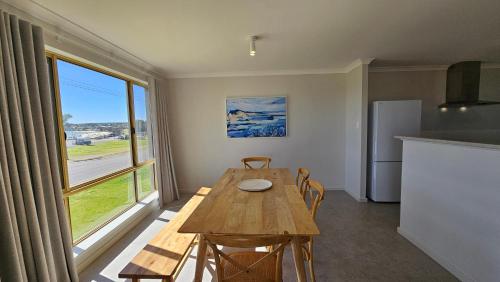 ein Esszimmer mit einem Holztisch und einem großen Fenster in der Unterkunft Pelican Shore Villa 3A- Kalbarri, WA in Kalbarri