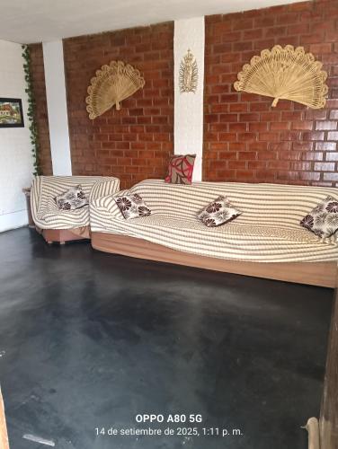 two beds sitting next to a brick wall at Casita de camucha in Chincha Baja
