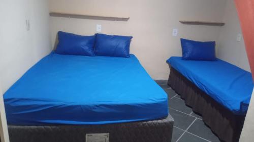 two beds in a room with blue pillows at Praia de Boraceia casa 2 Bertioga in Bertioga