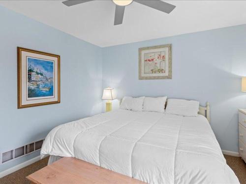 a white bedroom with a white bed and two pictures at Seabreeze village 5 in Dewey Beach