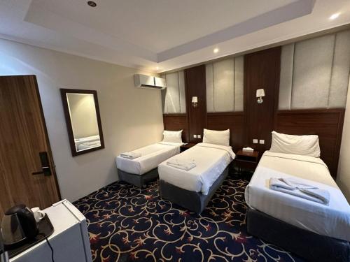 a hotel room with two beds and a television at Manasik Al Bait Hotel Makkah in Makkah