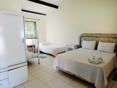 ein Schlafzimmer mit zwei Betten und einem Fernseher in der Unterkunft Pousada Viajantes do Tempo in Cunha