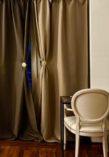 a chair next to a table and a curtain at CENTRO House in Alytus